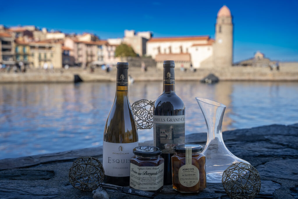 Bouteilles, bocaux et carafe du Cellier Dominicain devant le clocher de Collioure