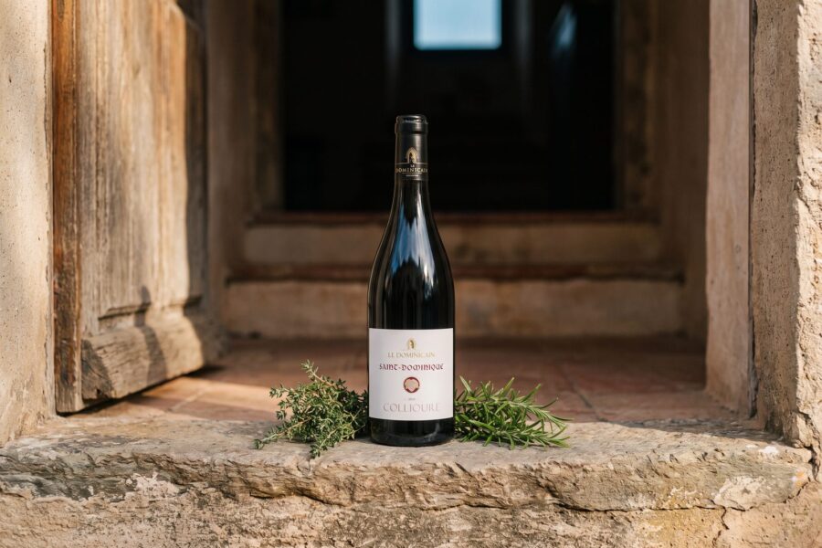 Bouteille de Collioure Saint-Dominique dans l'encadrement d'une porte ancienne, herbes de garrigue